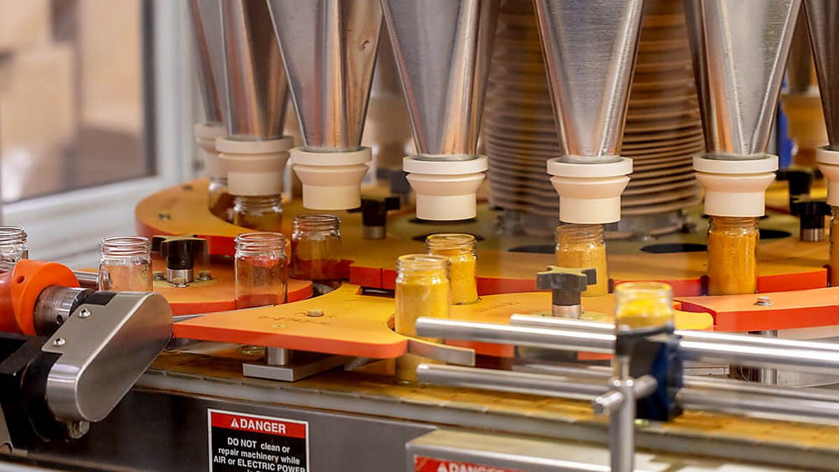 spice p[production facility at vanns spices, machine filling spice jars with private label spices