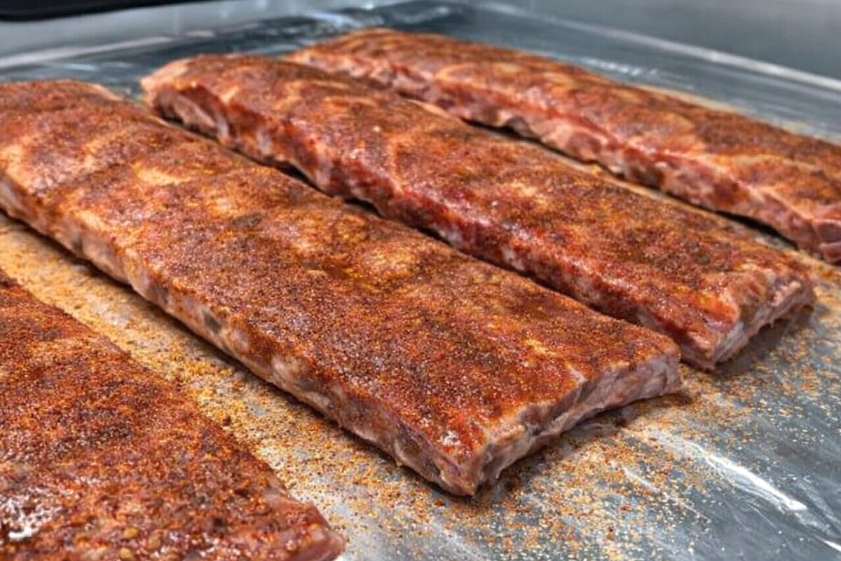 bbq ribs covered with seasoning on a sheet of aluminum foil