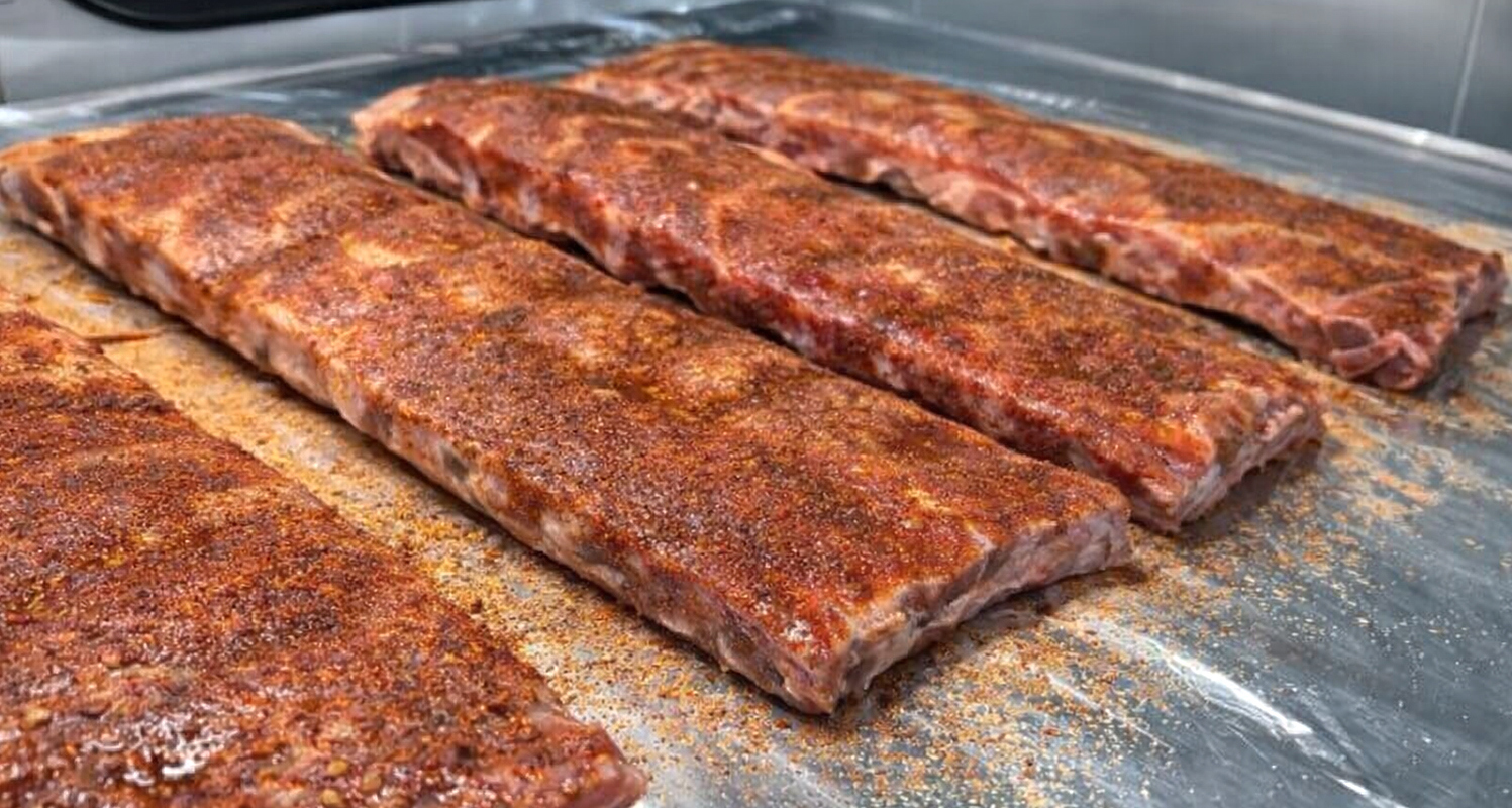 bbq ribs covered with seasoning on a sheet of aluminum foil
